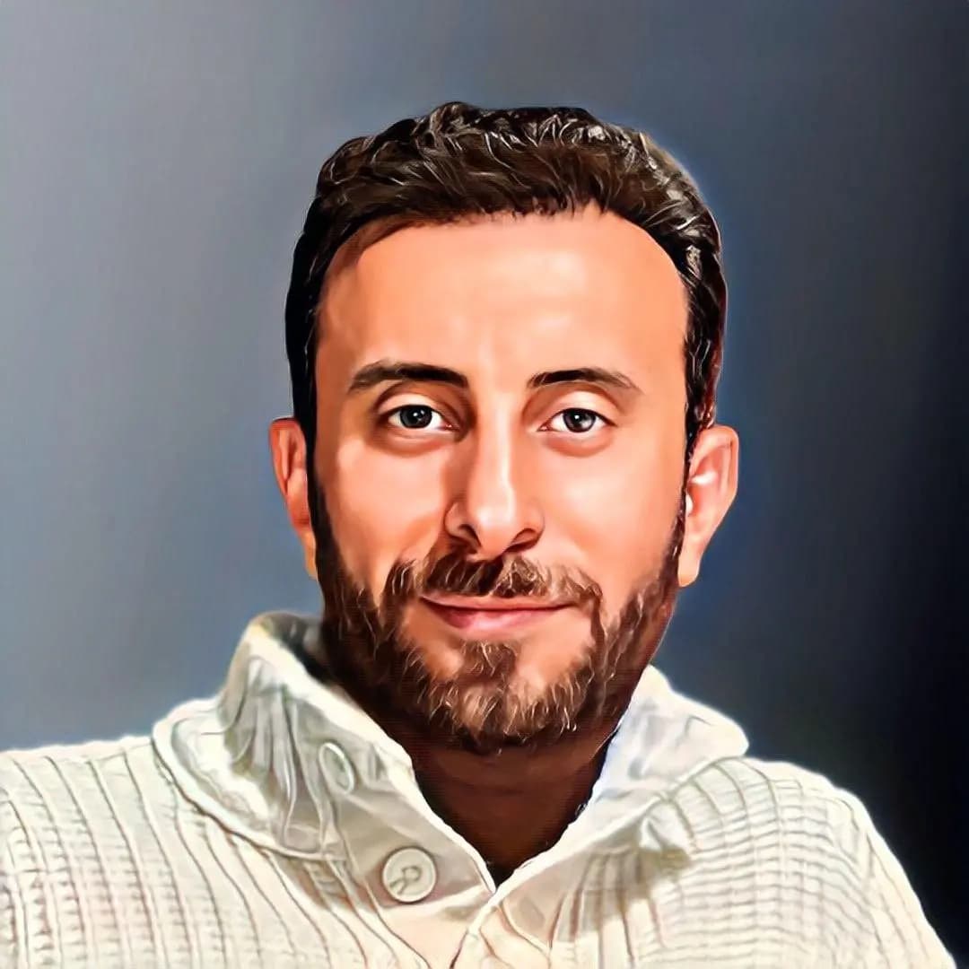 Essam Alsaloum working at his desk with a laptop in a casual office environment.